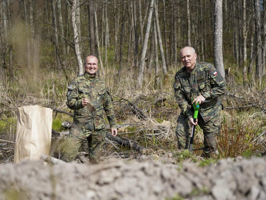 Dw&oacute;ch mężczyzn w mundurach leśnych sadzi drzewa w lesie na Mazurach.