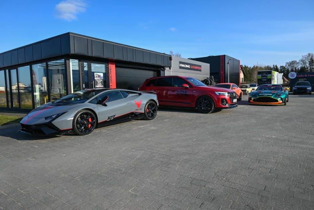 Wyścigowe Aston Martiny GT3 i GT4 na parkingu pod Olsztynem, przygotowane do start&oacute;w.