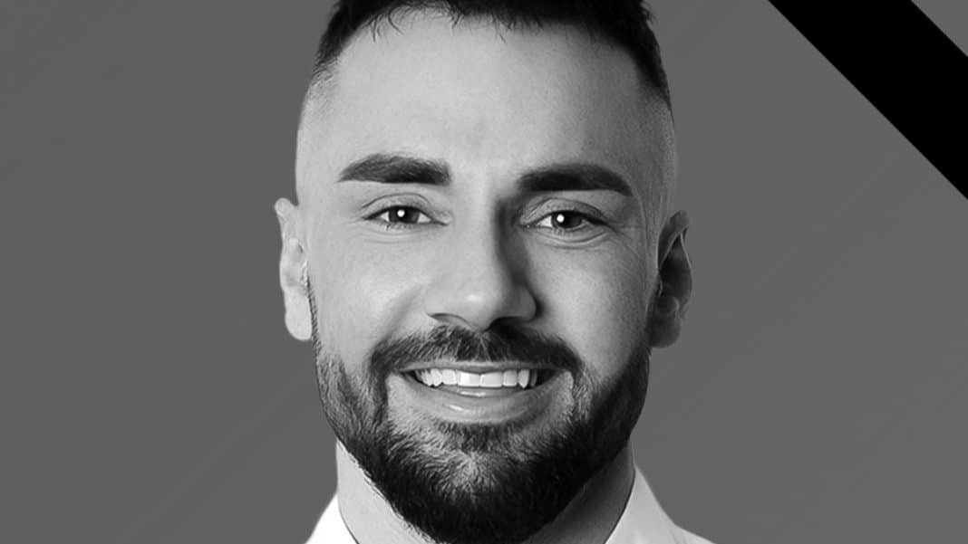 Portret mężczyzny z uśmiechem, czarno-białe zdjęcie, w tle szary kolor.