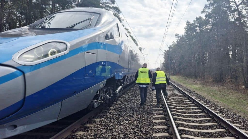 Pociąg Pendolino na torach, obok policjanci w odblaskowych kamizelkach, w miejscu tragedii.