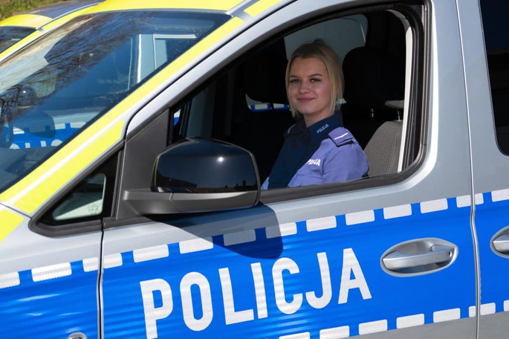 Policjantka w radiowozie na Mazurach, w policyjnym uniformie, za kierownicą pojazdu.