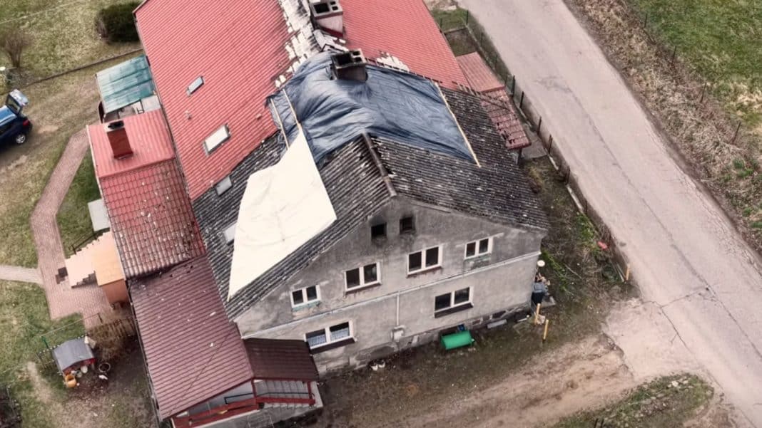 Zdjęcie z powietrza przedstawia uszkodzony dach domu po pożarze w Mostkowie.