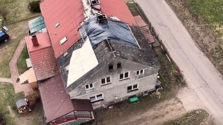 Zdjęcie z powietrza przedstawia uszkodzony dach domu po pożarze w Mostkowie.
