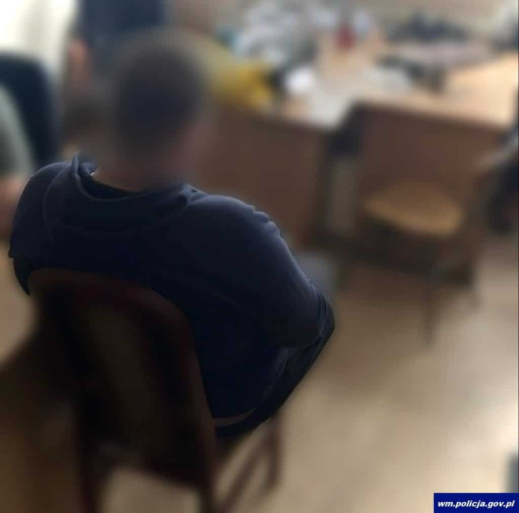 Nieostry, zamazany obraz mężczyzny siedzącego w pomieszczeniu, z widokiem na ulicę przez okno.