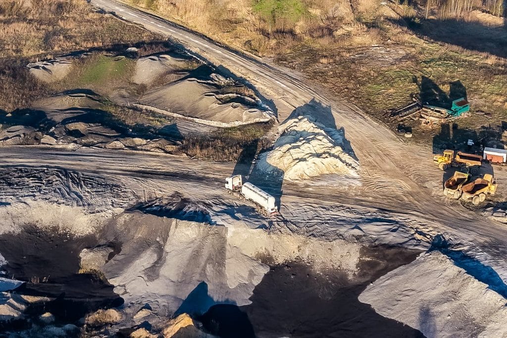 Zdjęcie z lotu ptaka przedstawia teren z ciężar&oacute;wkami i koparkami, prawdopodobnie miejsce akcji policyjnej.