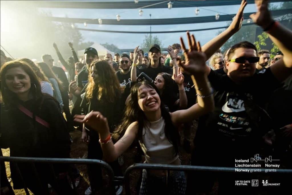Tłum ludzi na festiwalu muzycznym, tańczą i cieszą się wsp&oacute;lnie na otwartym powietrzu.