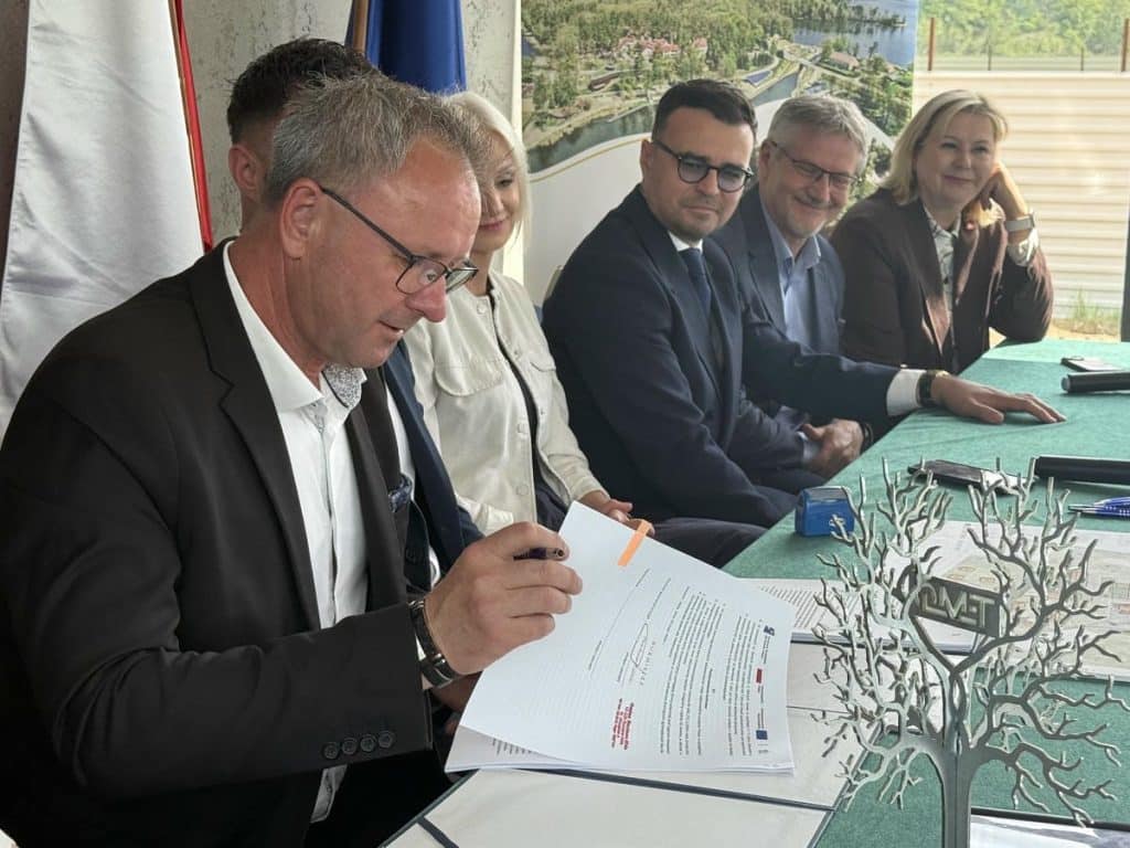 Grupa os&oacute;b podczas podpisywania umowy na budowę portu nad jeziorem Guzianka Wielka.