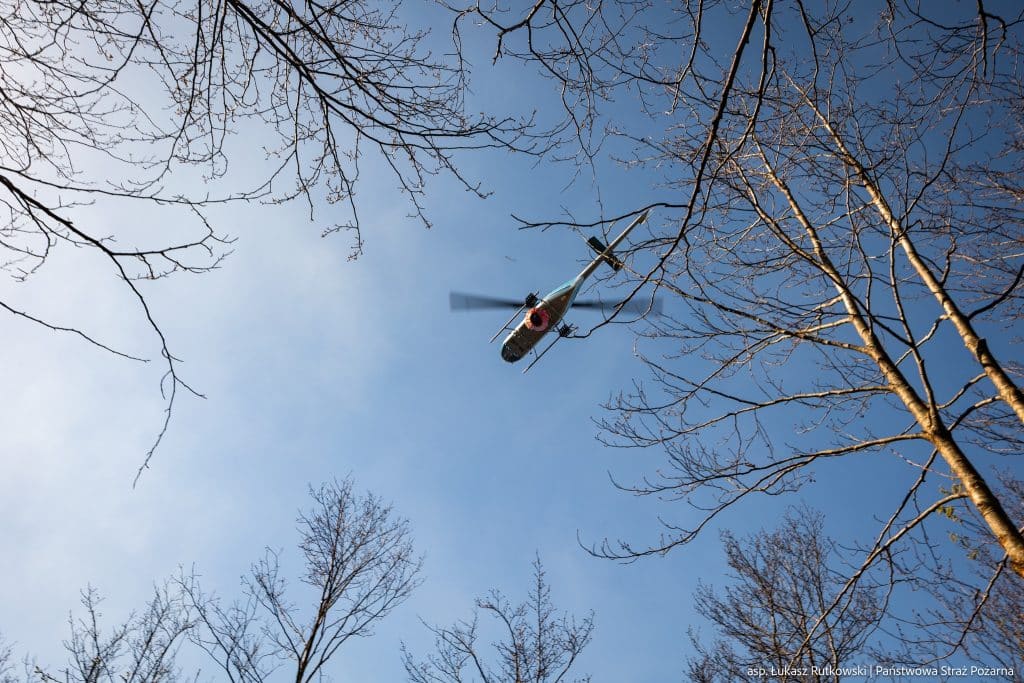 Helikopter nad drzewami podczas akcji ratowniczej na Mazurach.