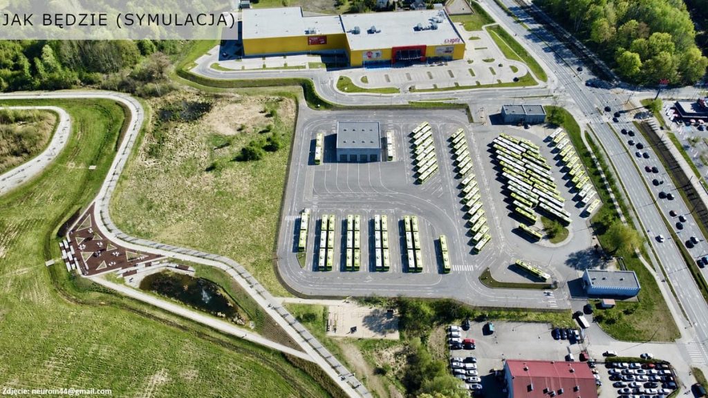 Widok na park z nowymi nasadzeniami drzew i parkingiem, w tle budynek i ulica.