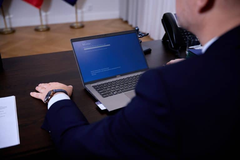 Osoba korzystająca z laptopa w biurze, wyświetlacz pokazuje komunikat o błędzie systemu.