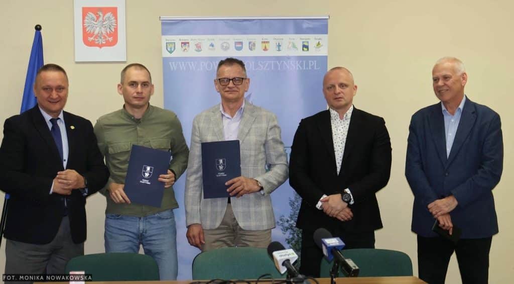 Grupa mężczyzn podczas podpisania um&oacute;w na inwestycje drogowe w powiecie olsztyńskim.