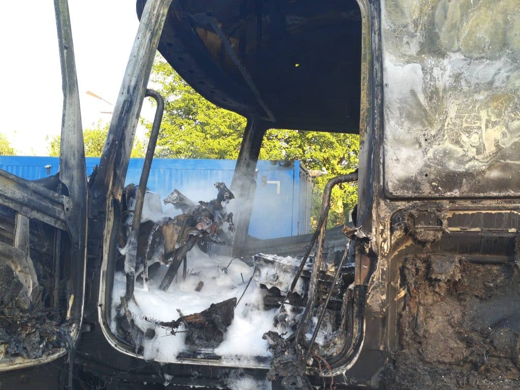 Spalona kabina ciężar&oacute;wki po pożarze na parkingu w Braniewie, widoczne zniszczenia i czarne ściany.