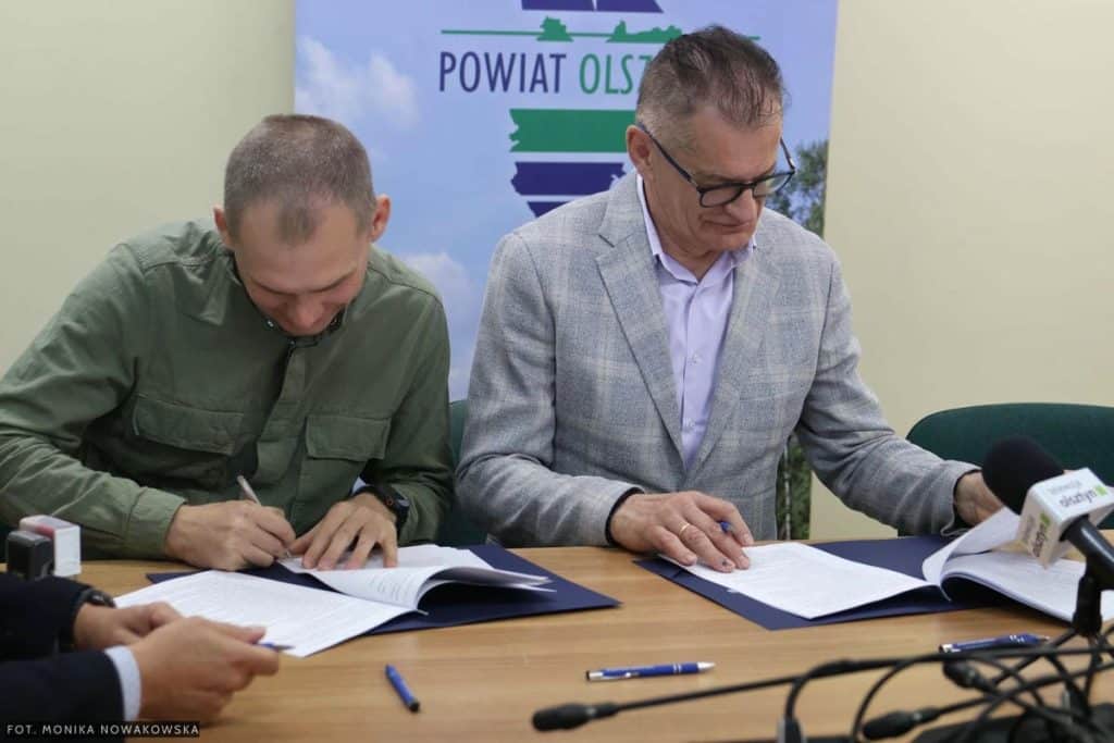 Zdjęcie przedstawia podpisanie um&oacute;w na remonty dr&oacute;g w gminach pod Olsztynem, z udziałem przedstawicieli powiatu.
