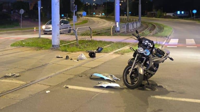 Motocykl i fragmenty uszkodzonego pojazdu na ulicy po wypadku w Elblągu.