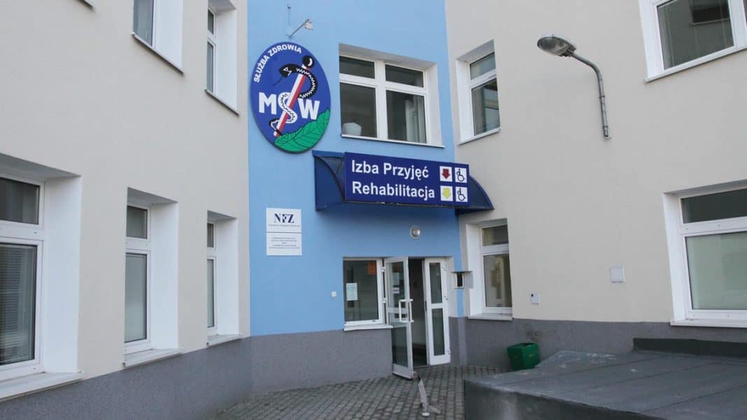 Widok z zewnątrz budynku szpitala z oznaczeniem izby przyjęć i rehabilitacji.
