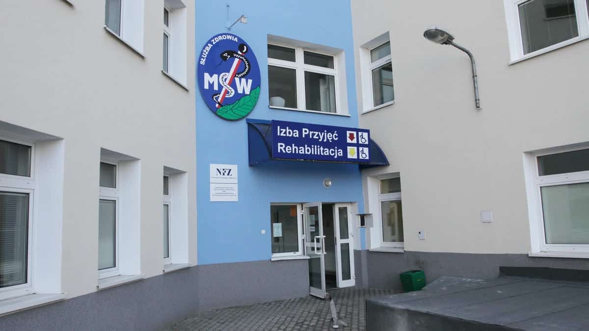 Widok z zewnątrz budynku szpitala z oznaczeniem izby przyjęć i rehabilitacji.