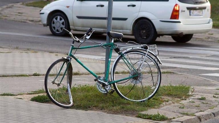 Rower leży na chodniku przy oznakowanym przejeździe, obok samochodu na rondzie Praw Kobiet w Ełku.