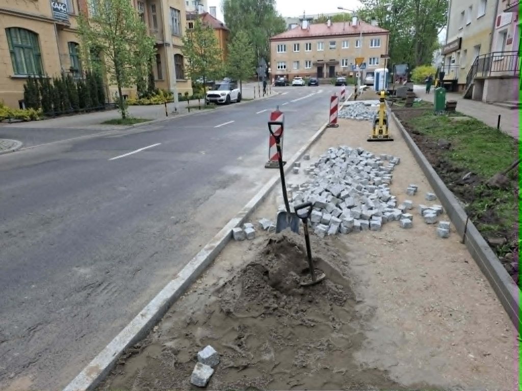 Prace drogowe na chodniku w centrum Olsztyna, układanie kostki brukowej, utrudnienia dla kierowc&oacute;w.
