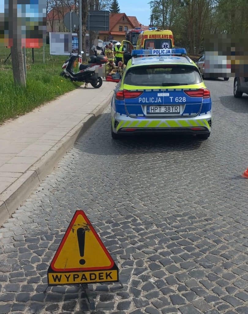 Miejsce zdarzenia na DK16 w Mikołajkach, służby ratunkowe i oznakowanie w pobliżu.