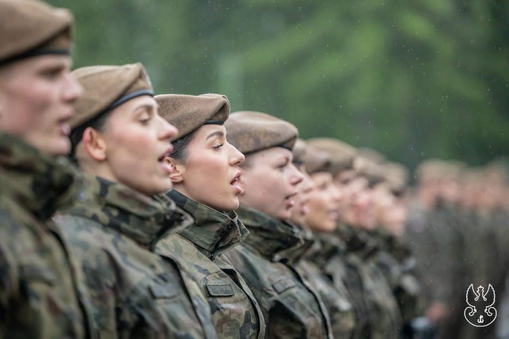 Żołnierze Obrony Terytorialnej w mundurach podczas uroczystości, w tle zieleń lasu.