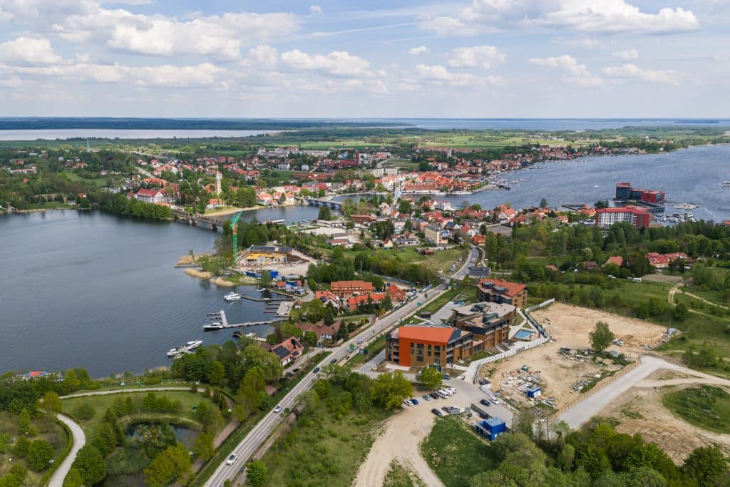 Widok na jezioro i rozwijającą się zabudowę w Mikołajkach na Mazurach.