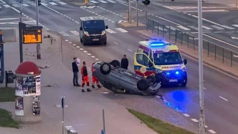 Samochód leżący na dachu na ul. Wilczyńskiego w Olsztynie, obok karetka i ratownicy.