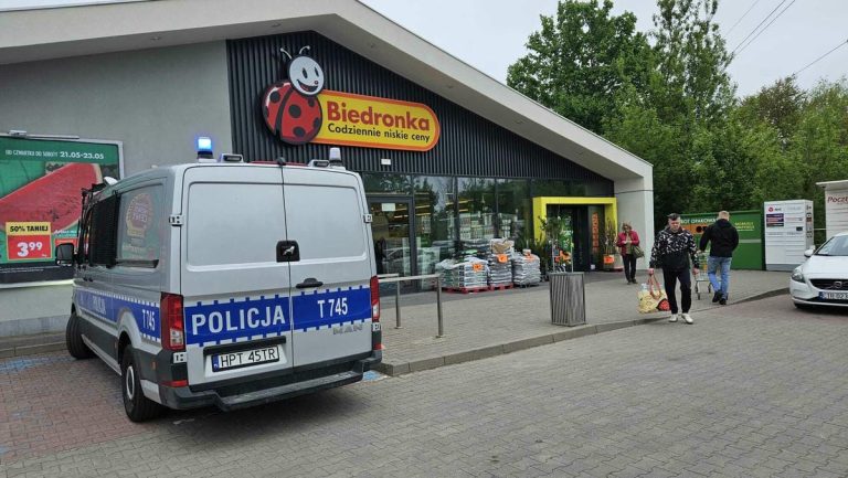 Widok na sklep Biedronka w Olsztynie z radiowozem policji przed wejściem.