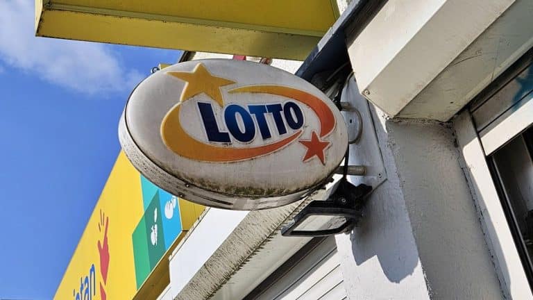Zbliżenie na znak kolektury Lotto na tle nieba i budynku.