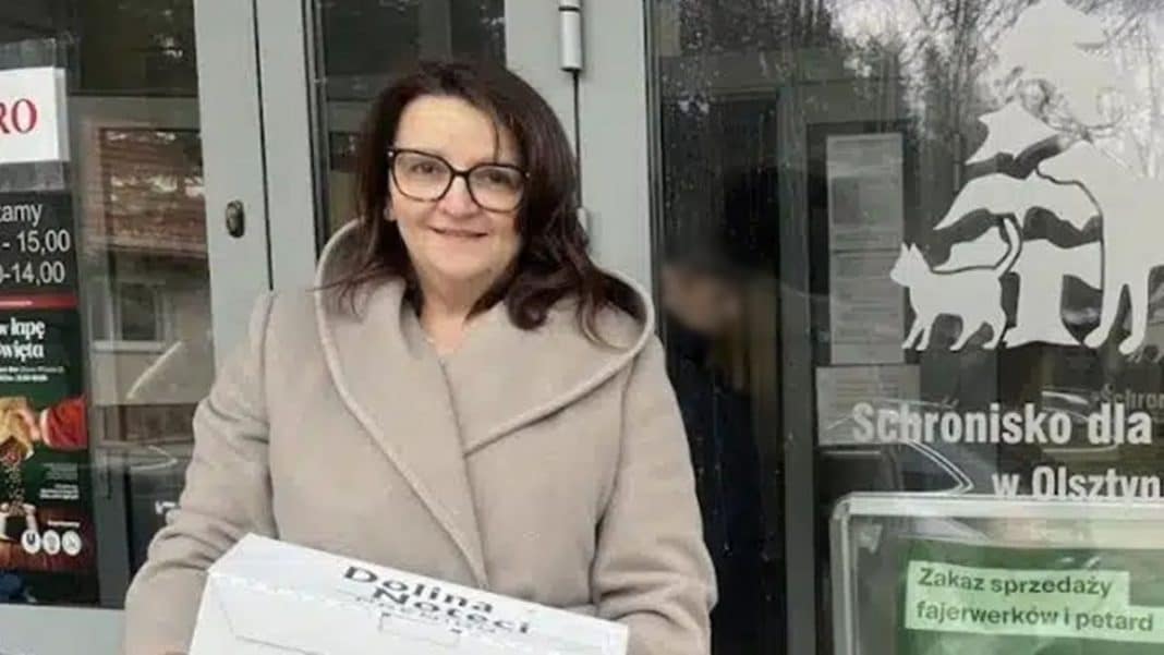Kobieta trzymająca kartonowe pudełko przed wejściem do schroniska dla zwierząt w Olsztynie.