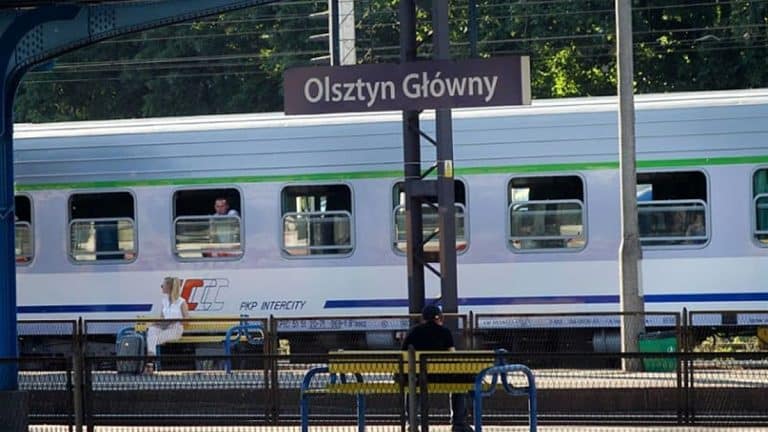 Pociąg PKP Intercity na stacji Olsztyn Gł&oacute;wny, widoczny peron i pasażerowie czekający na odjazd.