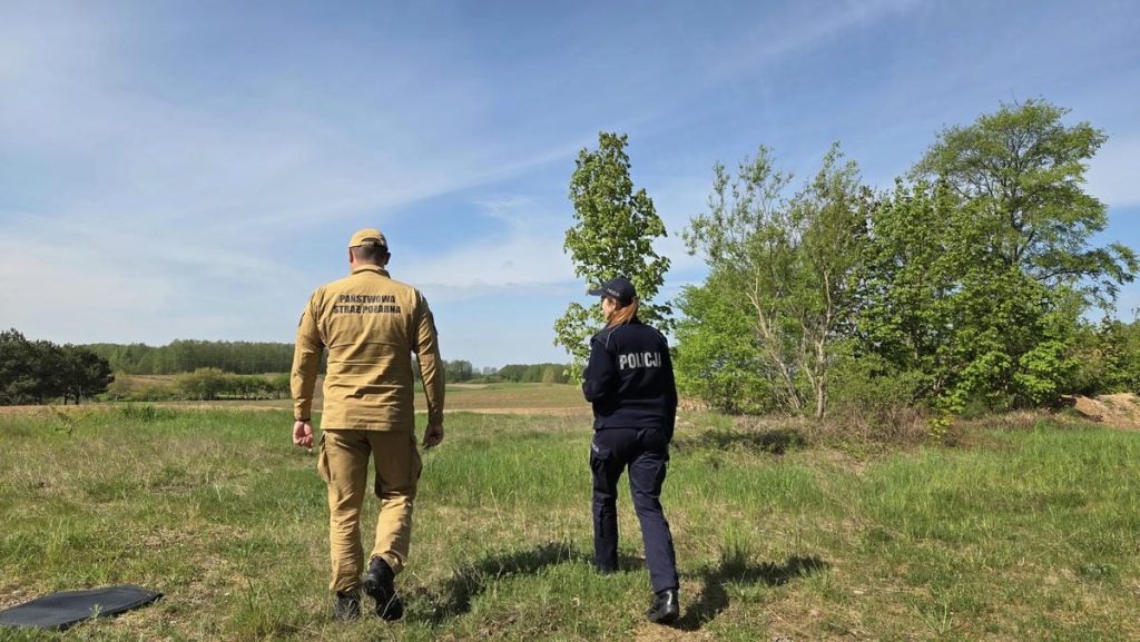 Strażak i policjant przeszukują teren na Mazurach podczas akcji poszukiwawczej.