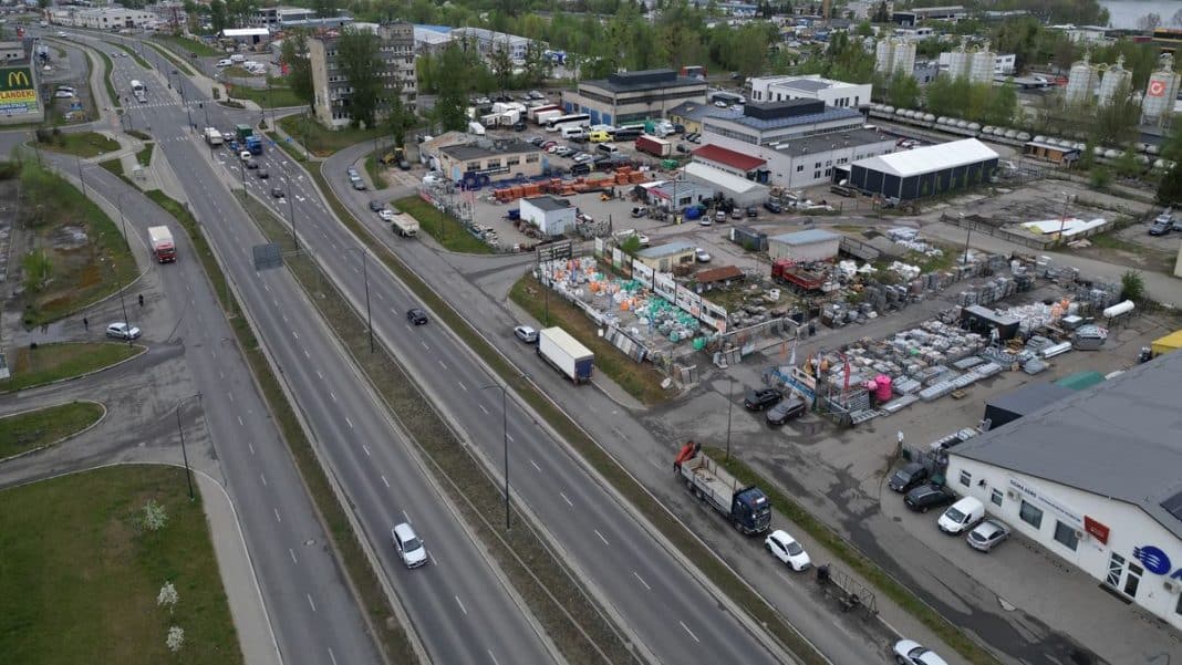 Widok na teren przemysłowy w Olsztynie z magazynami i placem z towarami, w tle ulice i budynki.