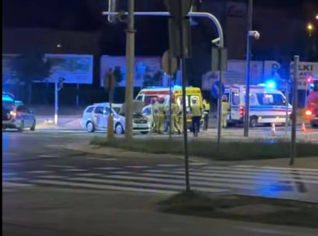 Widok na miejsce wypadku na skrzyżowaniu z karetkami i służbami ratunkowymi, nocą.