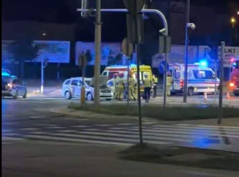 Widok na miejsce wypadku na skrzyżowaniu z karetkami i służbami ratunkowymi, nocą.