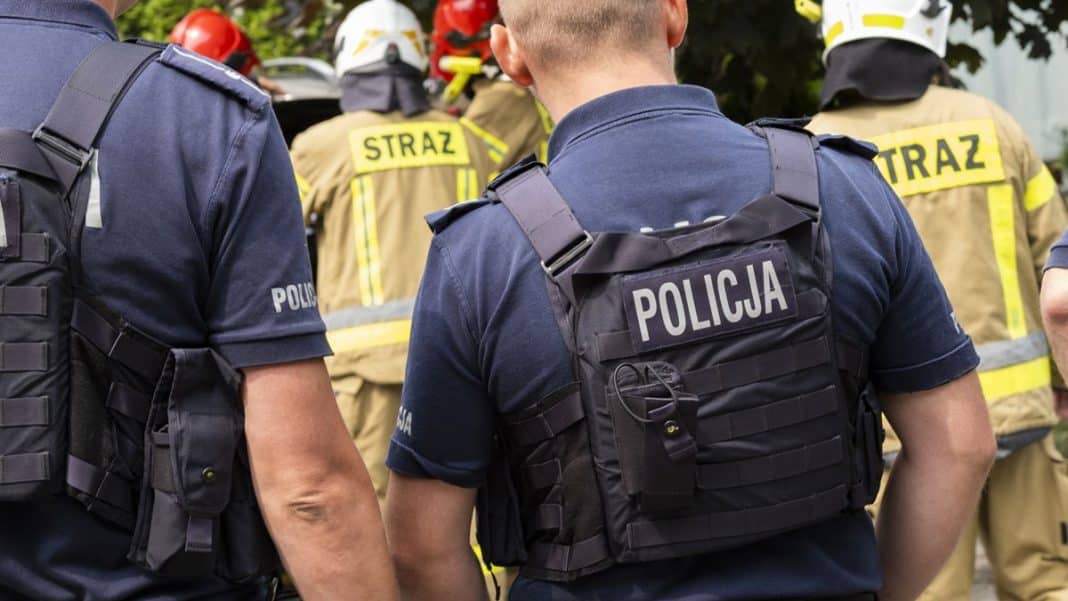 Służby ratunkowe na miejscu ewakuacji szkoły w Olsztynie, w tle strażacy i policja.