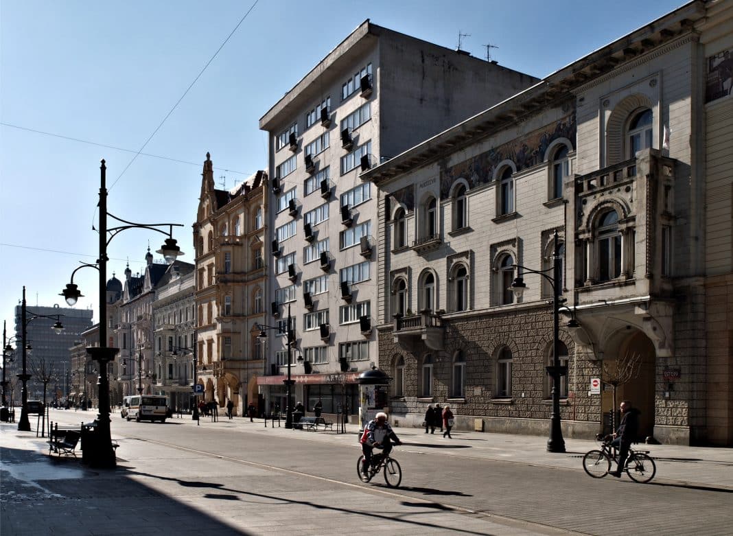 Ulica w centrum Łodzi z biurowcami i rowerzystami.