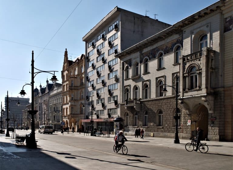 Ulica w centrum Łodzi z biurowcami i rowerzystami.