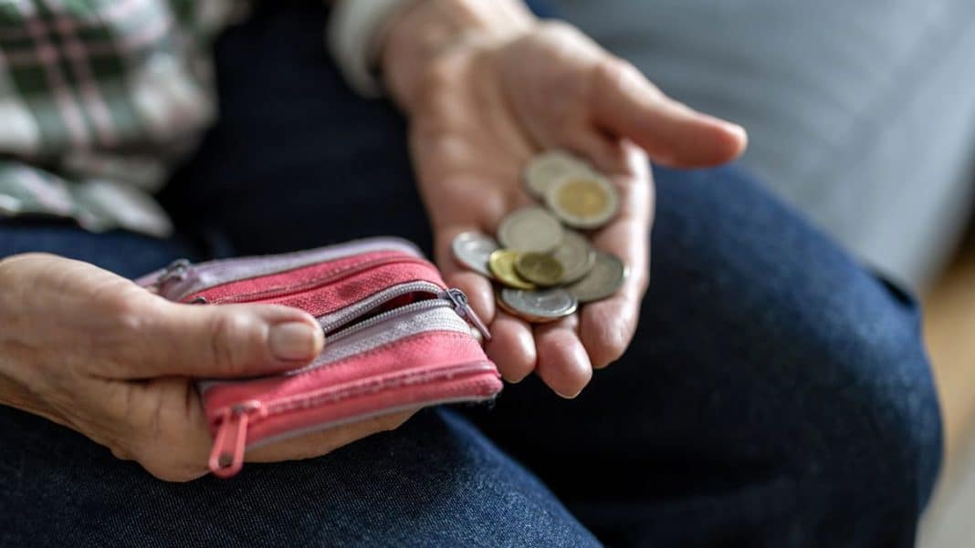 Dłoń trzymająca monety i portfel, symbol oszustwa finansowego seniora.