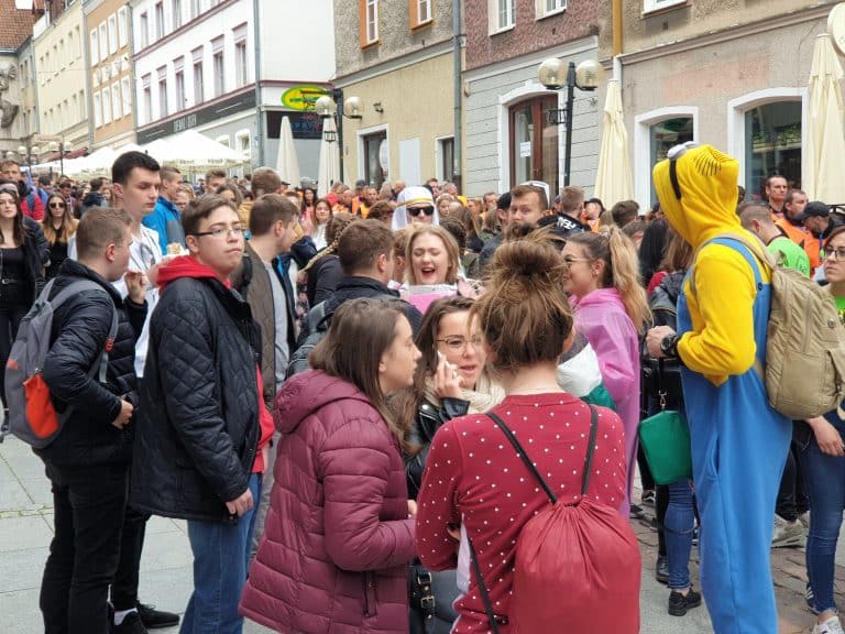 Tłum ludzi na ulicy Starego Miasta podczas wydarzenia plenerowego, w tle budynki i namioty.