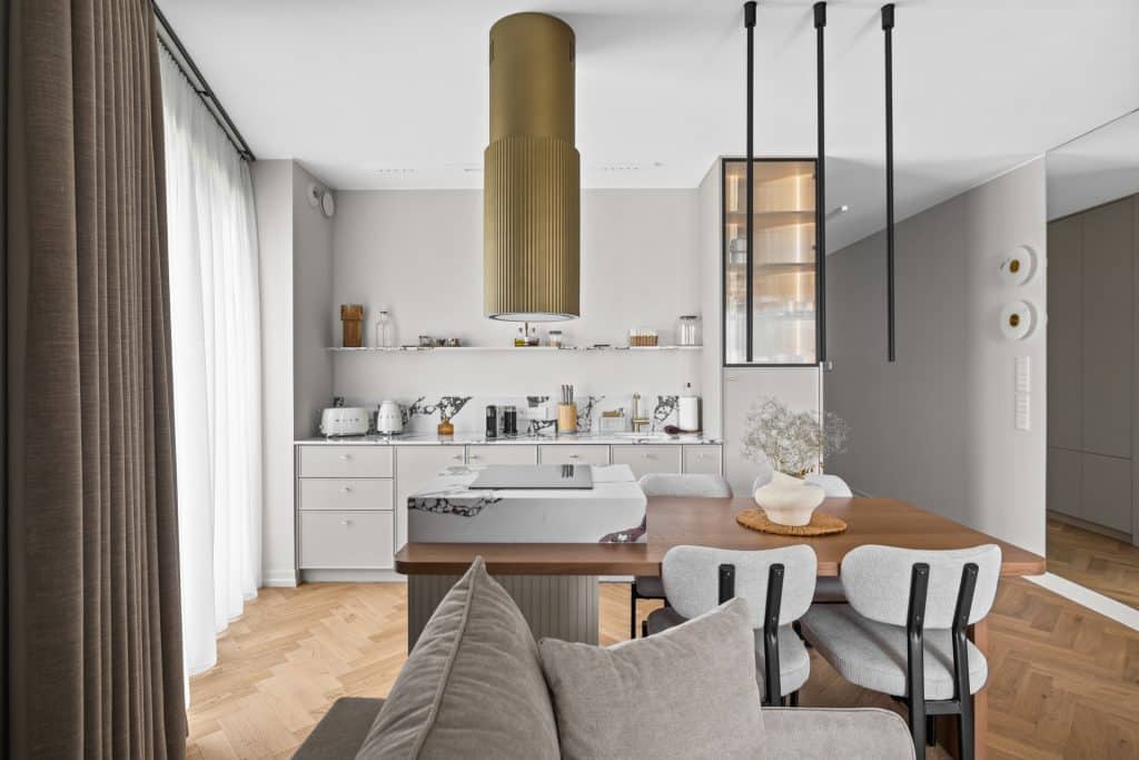 Wnętrze nowoczesnego apartamentu z kuchnią i jadalnią, jasne kolory, minimalistyczny wystrój, drewniany stół.