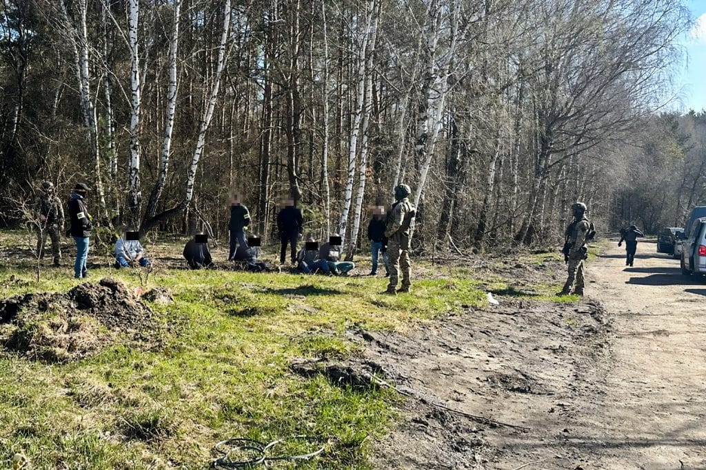 Funkcjonariusze CBŚP zatrzymują podejrzanych w lesie na Mazurach podczas akcji przeciwko nielegalnemu gospodarowaniu odpadami.