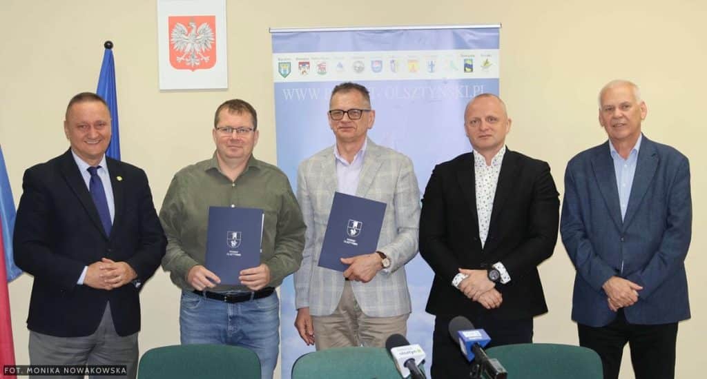 Grupa mężczyzn na spotkaniu podpisującym umowy na remonty dr&oacute;g w gminach pod Olsztynem.