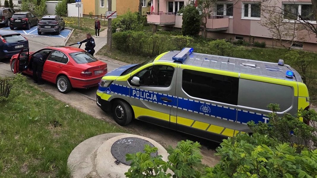 Policja zatrzymuje czerwone BMW na ulicy w centrum Olsztyna podczas pościgu.