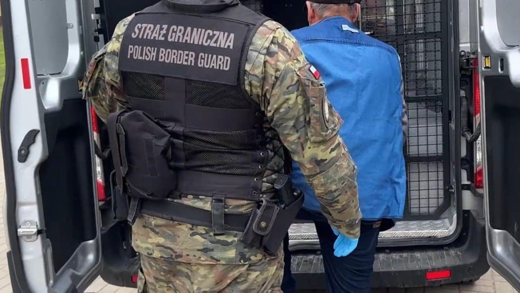 Funkcjonariusz Straży Granicznej eskortuje cudzoziemca do pojazdu na lotnisku.