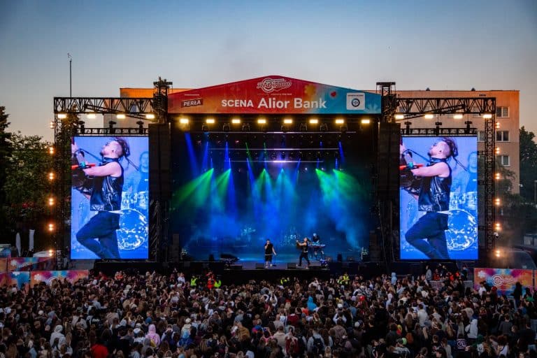 Widok na dużą scenę koncertową podczas festiwalu Kortowiada, z tłumem widzów przed sceną i efektami świetlnymi.