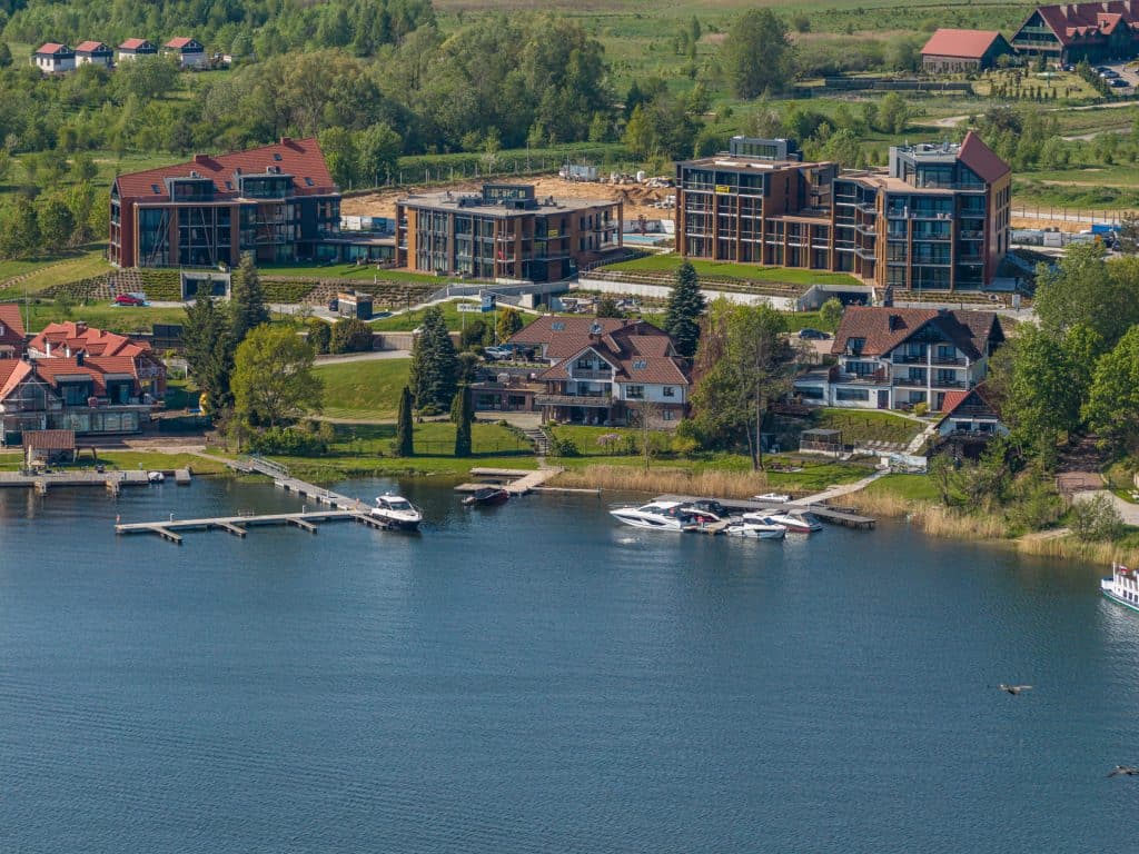 Nowoczesne apartamenty nad jeziorem na Mazurach, otoczone zielenią, z dostępem do mariny i łodzi.
