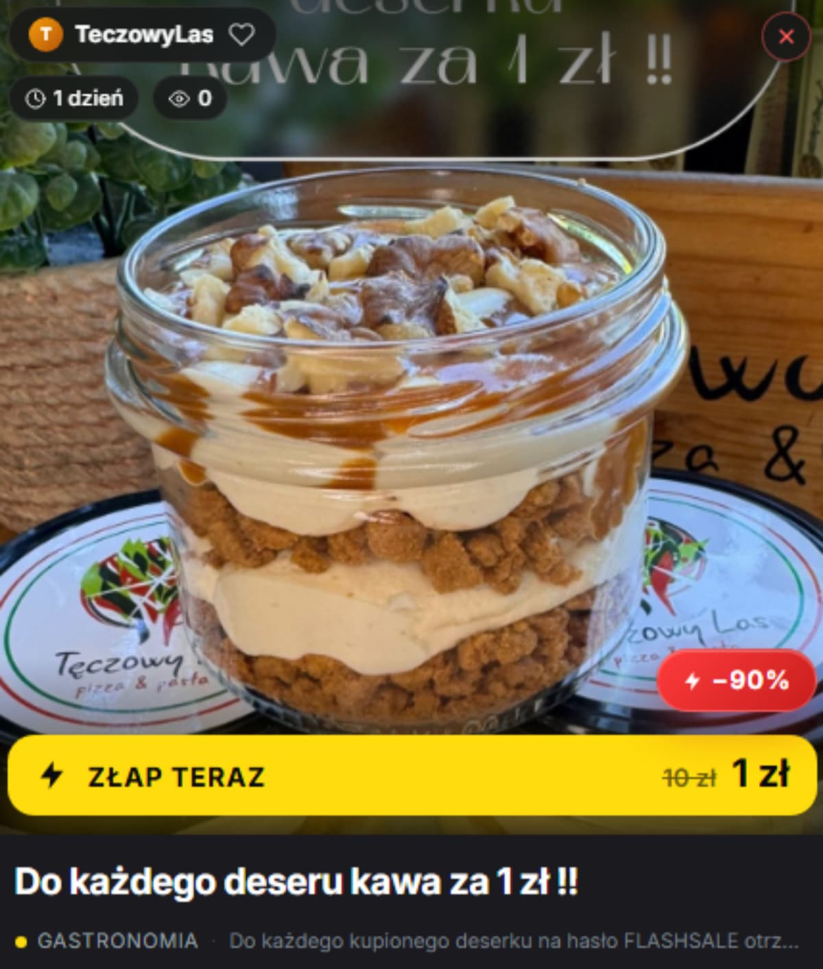 Słoik z deserem z warstwami kremu, ciastek i polewy, ustawiony na stoliku w kawiarni.