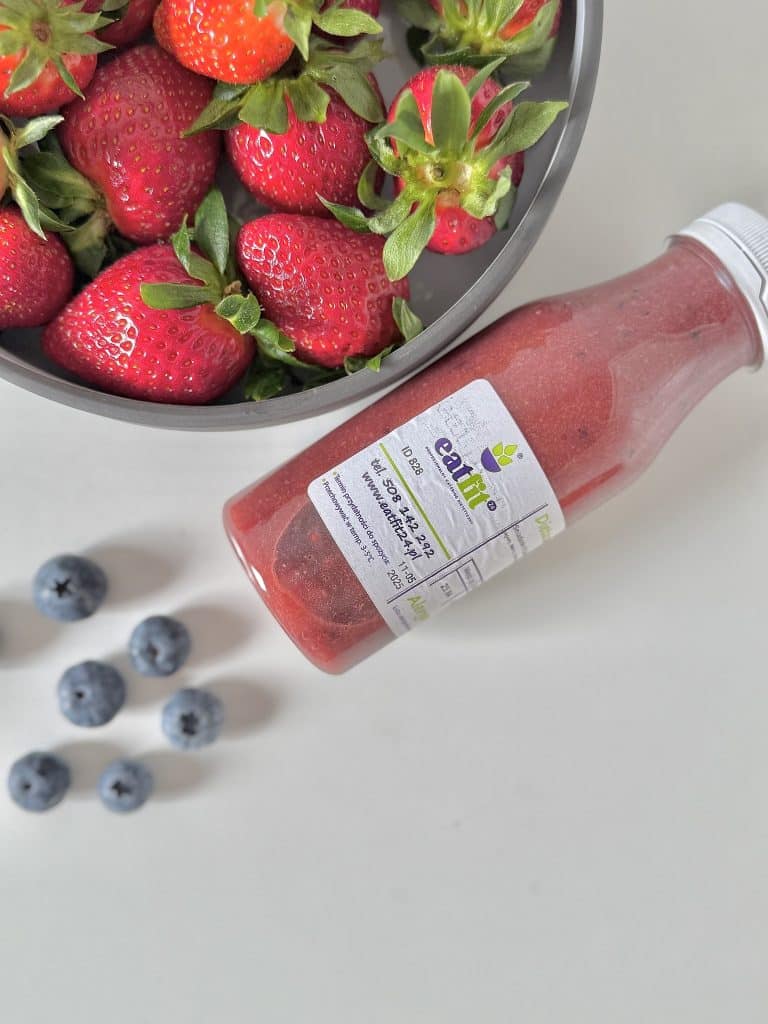 Truskawki, jagody i smoothie w butelce na białym tle.