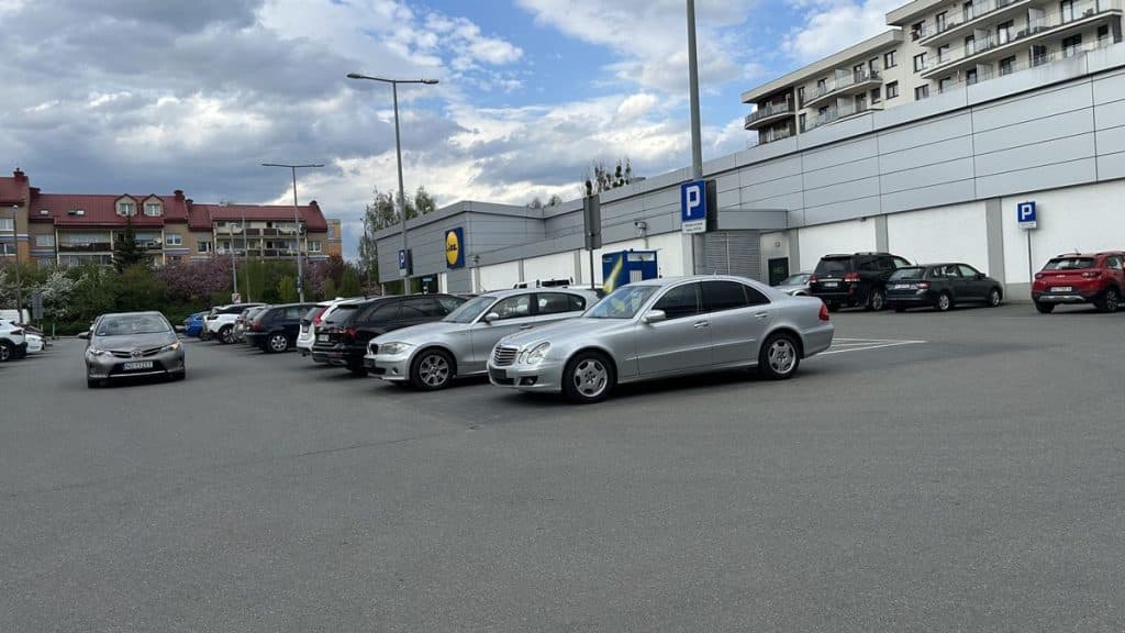 Parking lot przed sklepem Lidl przy ul. Barcza w Olsztynie, z kilkoma samochodami i budynkiem sklepu w tle.