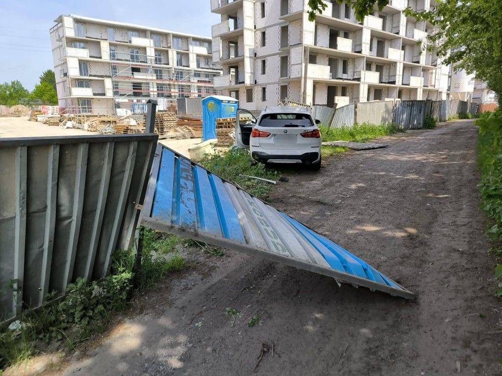 Samochód BMW wjechał w ogrodzenie placu budowy, na miejscu uszkodzone ogrodzenie i samochód.